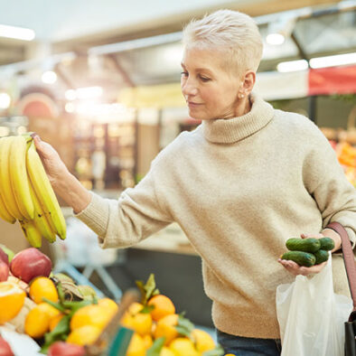 Woman grocery shopping looking at bananas