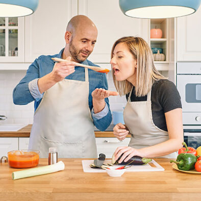 Couple in kitchen tasting food